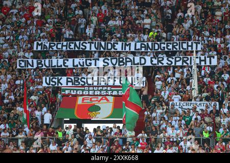 Augsburg, Deutschland. August 2024. Fanblock Augsburg, „Märchenstunde im Landgericht, Spruchband wegen dem aktuellen Polizisten-Prozeß, Schuß aus der Dienstpistole eines Polizisten vor der WWK-Arena vor etwa einem Jahr; FC Augsburg vs. Werder Bremen, 1. SPIELTAG; DFL-VORSCHRIFTEN VERBIETEN DIE VERWENDUNG VON FOTOS ALS BILDSEQUENZEN UND/ODER QUASI-VIDEO. Quelle: dpa/Alamy Live News Stockfoto