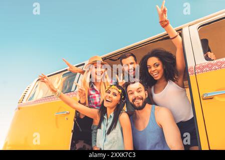 Jung wild und frei. Niedriger Blickwinkel auf eine Gruppe junger glücklicher Menschen, die Spaß miteinander haben, während sie im Retro-Minibus sitzen Stockfoto