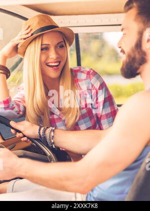 Genießen Sie einfache Freuden. Glückliches junges Paar, das sich mit einem Lächeln ansieht, während er in ihrem Kleinbus sitzt Stockfoto