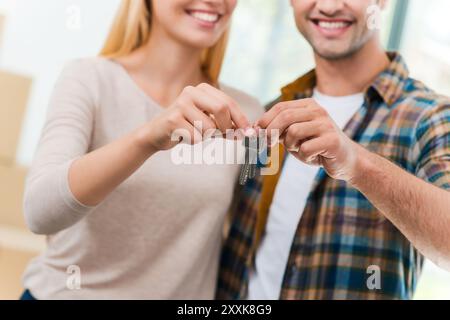 Schlüssel ihrer neuen Wohnung. Zugeschnittenes Bild eines jungen, liebevollen Paares, das Schlüssel hält und lächelt, während er in ihrem neuen Haus steht Stockfoto