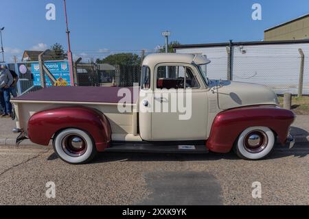 Rayleigh, Großbritannien. August 2024. Ein gut erhaltener amerikanischer Pickup-Truck aus der Mitte des 20. Jahrhunderts mit cremefarbenen und tiefroten zweifarbigen Lackierungen, Whitewall-Reifen und Chromakzenten, der während einer öffentlichen Autoshow in Großbritannien neben einem Geschäftsgebäude geparkt wurde. Der Lkw verfügt über eine kastanienbraune Gepäckraumabdeckung und abgerundete Kotflügel, die an das klassische Automobildesign erinnern. Amerikanisches Auto und Truck treffen sich in der Farm Fresh Garage. Bei der Veranstaltung können die Besitzer ihre Fahrzeuge mitbringen, damit die Besucher einen Blick aus der Nähe werfen können. Penelope Barritt/Alamy Live News Stockfoto