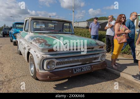 Rayleigh, Großbritannien. August 2024. Ein verwitterter Chevrolet Pickup mit verblichener grün-weißer Farbe parkt am Straßenrand während eines Oldtimer-Events in Großbritannien. Der Lkw trägt das Kennzeichen „LHH 265D“ und zeigt Anzeichen von Alterung und Rost, die an die Americana der Mitte des 20. Jahrhunderts erinnern. Hinter dem Fahrzeug ist ein blaues Oldtimerfahrzeug zu sehen, während mehrere Personen vom Bürgersteig aus beobachten, was auf ein Gemeindetreffen oder eine Autoausstellung hindeutet. Amerikanisches Auto und Truck treffen sich in der Farm Fresh Garage. Bei der Veranstaltung können die Besitzer ihre Fahrzeuge mitbringen, damit die Besucher einen Blick aus der Nähe werfen können. Penelope Barritt/Alamy Live News Stockfoto