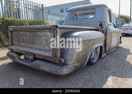 Rayleigh, Großbritannien. August 2024. Stark modifizierter Chevrolet Pickup-Truck mit abgesenkter Federung, der in der Nähe eines Industriegebäudes geparkt ist. Der Lkw verfügt über eine verwitterte Metallic-Oberfläche, spezielle Räder und ein auffälliges „CHEVROLET“-Logo an der Heckklappe. Ästhetische Änderungen und Leistungsänderungen spiegeln die Kultur der Fahrzeugrestaurierung und -Anpassung wider. Amerikanisches Auto und Truck treffen sich in der Farm Fresh Garage. Bei der Veranstaltung können die Besitzer ihre Fahrzeuge mitbringen, damit die Besucher einen Blick aus der Nähe werfen können. Penelope Barritt/Alamy Live News Stockfoto