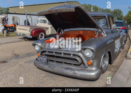 Rayleigh, Großbritannien. August 2024. Ein verwitterter 1957er Chevrolet Pickup mit offener Motorhaube, der freiliegende Motorkomponenten während einer öffentlichen Automobilausstellung in Großbritannien zeigt. Die patinierte Oberfläche und die mechanische Sichtbarkeit des Lkws deuten auf eine laufende Restaurierung hin oder sind stolz auf seine ursprüngliche Konstruktion. Amerikanisches Auto und Truck treffen sich in der Farm Fresh Garage. Bei der Veranstaltung können die Besitzer ihre Fahrzeuge mitbringen, damit die Besucher einen Blick aus der Nähe werfen können. Penelope Barritt/Alamy Live News Stockfoto