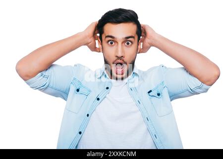 Oh nein! Schockierter junger Indianer, der Hände hinter dem Kopf hält und den Mund offen hält, während er vor weißem Hintergrund steht Stockfoto