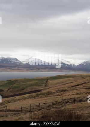 Eine ruhige Landschaft mit schneebedeckten Bergen und ruhigem Wasser unter bewölktem Himmel, die die Ruhe der Natur an einem abgelegenen Ort darstellt. Stockfoto