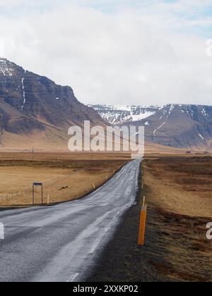 Ein atemberaubendes Bild einer verwinkelten Landstraße mit einer weiten Landschaft mit zerklüfteten Bergen in der Ferne, eine perfekte Landschaft für Outdoor-Enthusiasten Stockfoto