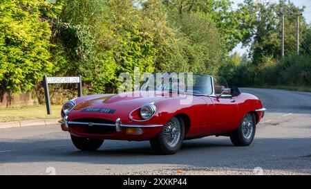 Whittlebury, Northants., Großbritannien - 25. August 2024: 1969 roter Jaguar E-Typ, der auf einer britischen Landstraße fährt. Stockfoto