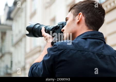 Die Schönheit einfangen. Rückansicht eines jungen Mannes, der etwas fotografiert, während er draußen steht Stockfoto