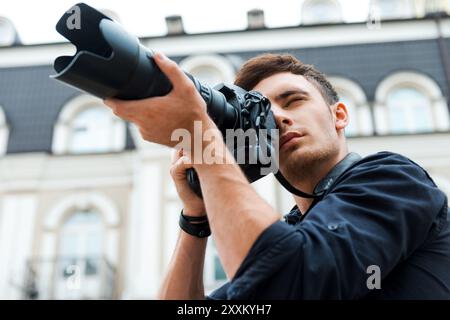 Machen Sie eine perfekte Aufnahme. Niedriger Blickwinkel eines jungen Mannes, der etwas fotografiert, während er draußen steht Stockfoto