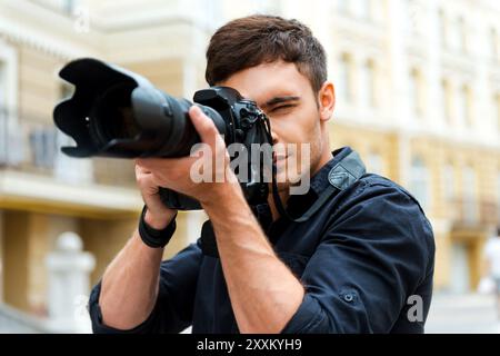 Fotografie ist meine Leidenschaft. Selbstbewusster junger Mann, der etwas fotografiert, während er draußen steht Stockfoto