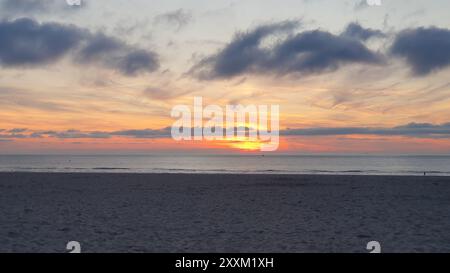 Wunderschöner Strand in Belgien mit Sonnenuntergang. Auf dem Sand in der Nähe des Wassers zu laufen. Viele Wolken über dem Meer. Stockfoto