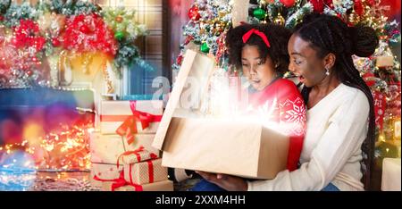 Afrikanische amerikanische Mutter und Tochter Eröffnung scheint Weihnachten Geschenkverpackung Stockfoto