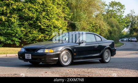 Whittlebury, Northants., Großbritannien - 25. August 2024: 1994 schwarzer Ford Mustang Auto fährt auf einer britischen Landstraße. Stockfoto