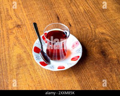 Blick über dem Zimmer auf türkischen Tee in einem kleinen Glas auf Untertasse auf Holztisch Stockfoto