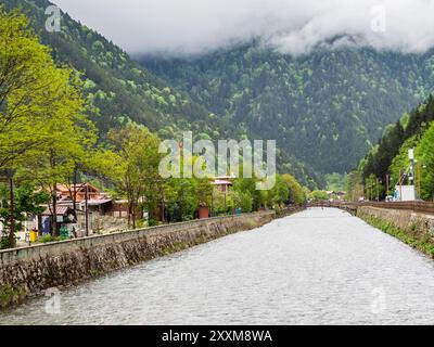 Wasserkanal im Dorf Uzungol in grün bewachsenen Bergen im Bezirk Caykara der Provinz Trabzon, Türkei an bewölktem Sommertag Stockfoto