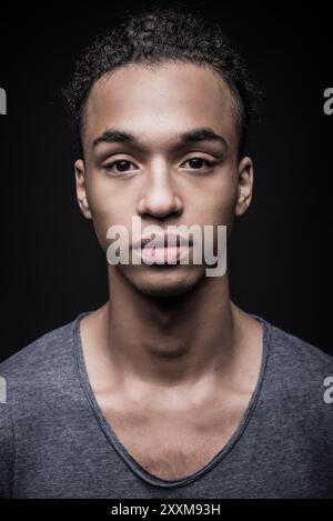 Reiner Look. Porträt eines jungen Afrikaners, der in die Kamera blickt, während er vor schwarzem Hintergrund steht Stockfoto
