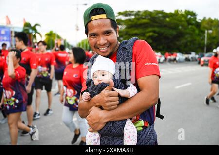 Kota Kinabalu, Malaysia. August 2024. Ein Mann, der ein Baby hält, nimmt am 2024 25. August 2024 am Freundschaftslauf zwischen Malaysia und China in Kota Kinabalu, Sabah, Malaysia Teil. Mehr als 5.000 Teilnehmer nahmen am Sonntag an der Freundschaftsrunde zwischen Malaysia und China 2024 in Kota Kinabalu, Sabah, Malaysia Teil, um eine jährliche Veranstaltung zu erweitern, die den 50. Jahrestag der Gründung bilateraler Beziehungen feiert. Quelle: Cheng Yiheng/Xinhua/Alamy Live News Stockfoto