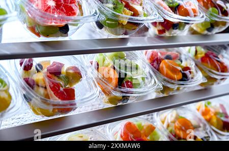 Plastikboxen mit vorverpackten Obstsalaten, in einem handelsüblichen Kühlschrank zum Verkauf aufgemacht Stockfoto