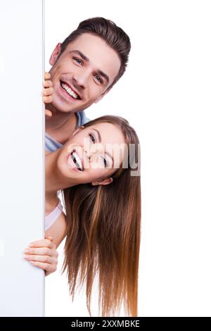 Schauen Sie nach draußen. Wunderschönes junges, liebevolles Paar, das aus dem Kopierraum blickt, während es vor weißem Hintergrund steht Stockfoto