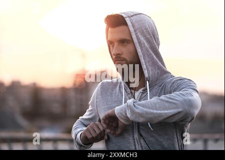 Trainieren an der frischen Luft. Selbstbewusster junger Mann, der seinen Körper dehnt, bevor er im Freien läuft Stockfoto