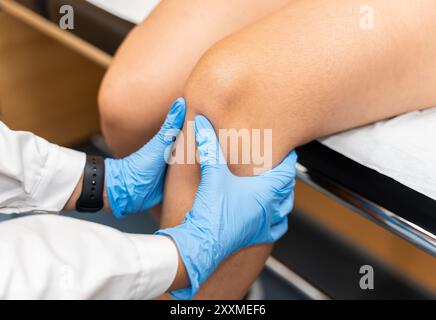 Ein orthopädischer Traumaarzt untersucht das Kniegelenk einer schmerzhaften Frau Stockfoto