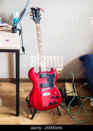 Rote elektrische Gitarre und Verstärker im Zimmer einer Wohnwohnung in Tiflis City, Georgia Stockfoto