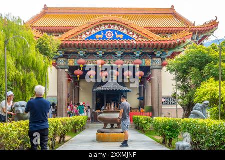 Blick auf einen Pfad durch einen Garten, der sich einem der farbenfrohen Tempel im chinesischen Stil im Kek Lok Si Temple Complex in Penang, Malaysia, nähert Stockfoto