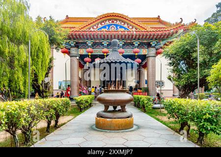 Blick auf einen Pfad durch einen Garten, der sich einem der farbenfrohen Tempel im chinesischen Stil im Kek Lok Si Temple Complex in Penang, Malaysia, nähert Stockfoto