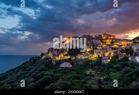 Panoramablick auf Pisciotta, beleuchtet am Abend mit dem Meer im Hintergrund. Cilento, Kampanien, Süditalien. Stockfoto