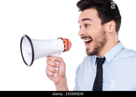 Gute Neuigkeiten. Seitenansicht eines glücklichen jungen Mannes in Hemd und Krawatte, der Megaphon hält und schreiend vor weißem Hintergrund steht Stockfoto