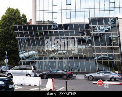 Tiflis, Georgien - 25. Juli 2024: Reflexion geparkter Autos in der Spiegelwand des modernen Bürozentrums in Tiflis City, Georgien am Sommertag Stockfoto