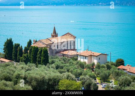 Malerischer Blick auf die Kirche Brenzone sul Garda, Italien mit dem türkisfarbenen Gardasee im Hintergrund Stockfoto