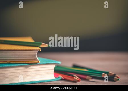 Bücher, Schreibwaren liegen auf dem Tisch vor dem Hintergrund einer schwarzen Tafel. Bildung, 1. September, neues akademisches Jahr Stockfoto