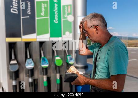 Reifer Mann, der sich Sorgen macht und Geld zählt und Euro-Banknoten hält, um hohe Benzinpreise zu zahlen. Mangel an Geld für Benzin und Kraftstoff. Teures Benzin. Stockfoto