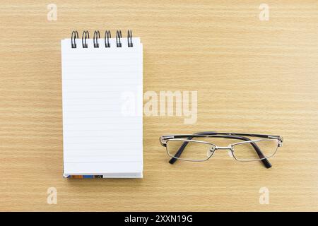 Brillen und Notizblock mit leeren Seite auf Holz Tisch Stockfoto