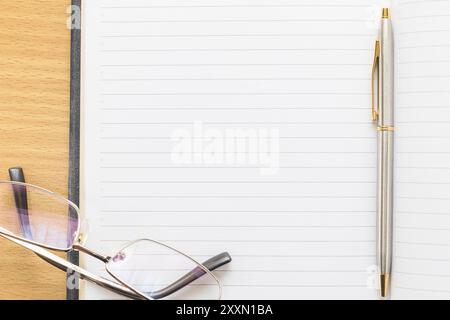 Brillen und Stift auf Notepad mit leeren Seite auf Holz Tisch Stockfoto