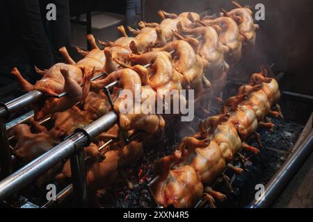 Eine Reihe Hühner, die auf Spießen über glühenden Kohlen rösten. Stockfoto