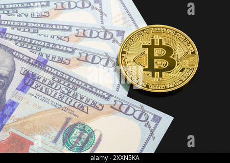 Goldene Bitcoins und US-Banknoten von hundert Dollar. Nahaufnahme von metallglänzenden Bitcoin-Krypto-Währungsmünzen und US-Dollar Stockfoto