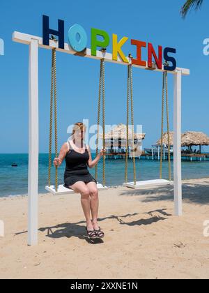 Frau am Strand sitzt auf Swing, Hopkins, Belize Stockfoto