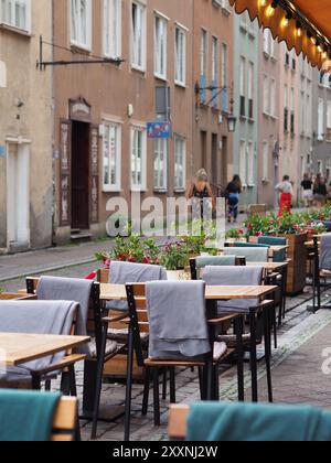 Danzig, Polen - 13. Juli 2024: Eine Café-Szene mit Holztischen und -Stühlen, über denen Decken hängen, vor einer bezaubernden Straße Stockfoto