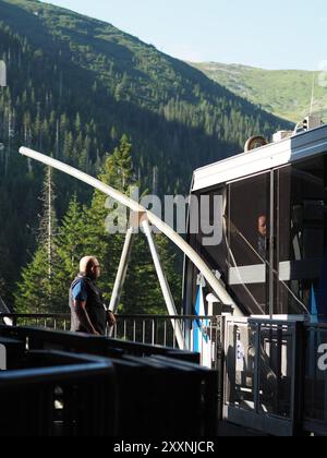 Kasprowy Wierch, Polen - 27. Juli 2024: Ein Seilbahnbetreiber steht in der Nähe der Seilbahnstation mit einer riesigen und atemberaubenden Bergkulisse Stockfoto