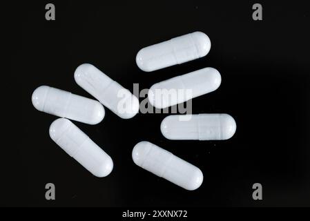 Weiße Vitamine ergänzen Kapseln auf schwarzem Hintergrund Stockfoto
