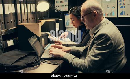 Detectives, die Tatorte anhand von Archivbeweisen und Zeugenaussagen nachstellen, erstellen eine Zeitachse, um Ereignisse in Echtzeit zu sehen. Das Agenten-Team arbeitet an der Bundesuntersuchung im Archiv. Kamera B.. Stockfoto