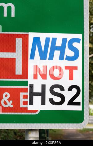 A413 Stoke Mandeville Straßenschild für Stoke Mandeville Hospital und Stadium mit Anti HS2 Schild angebracht. Auf dem Anti-HS2-Schild steht NHS, nicht HS2. Wer auch immer das NHS-NICHT-HS2-Zeichen herstellte, glaubte wahrscheinlich, dass das Geld, das für HS2 ausgegeben wurde, zur Unterstützung des NHS verwendet werden sollte. Ein paar Kilometer entfernt am Stadtrand von Aylesbury beginnt die zweite Woche der HS2-Schließung der A418, was zu extremen Groll bei den Anwohnern, Verkehrsverzögerungen und Umleitungen sowie Geschäftsverlusten vor Ort führt. Quelle: Stephen Bell/Alamy Stockfoto