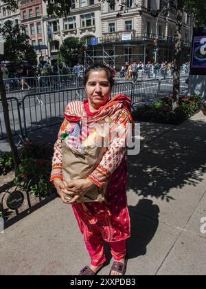 New York, New York, USA. August 2024. Eine Pakistanerin – Amerikanerin in traditioneller Kleidung, die eine Tasche mit Erfrischungen hält und die amerikanische Flagge vor der Kamera posiert. Die Pakistan Independence Day Parade fand heute auf der Madison Avenue statt, beginnend am 38. Und endet in der 23. Straße, Madison Square Park, Manhattan. Die Feier erinnert an Pakistans Emanzipation und Unabhängigkeit vom Vereinigten Königreich und erklärte am 14. August 1947 zum souveränen Staat. Quelle: ZUMA Press, Inc./Alamy Live News Stockfoto