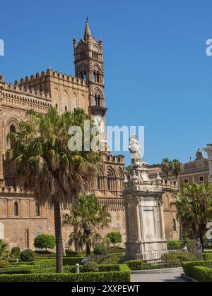 Kathedrale mit Statue und Uhrenturm sowie Palmen und Garten im Vordergrund unter blauem Himmel, palermo, sizilien, mittelmeer, italien Stockfoto