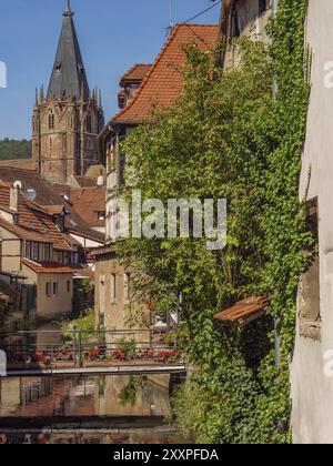 Historische Stadt mit Kirchturm, umgeben von Häusern, einem Fluss und üppigem Efeu, Weissenburg, Elsass, Frankreich, Europa Stockfoto