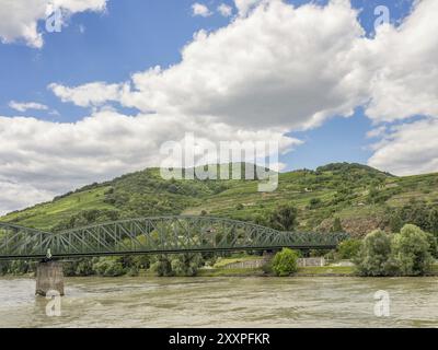 Metallbrücke über den Fluss mit grünen Hügeln und bewölktem Himmel im Hintergrund, Duernstein, Wachau, Donau, Österreich, Europa Stockfoto