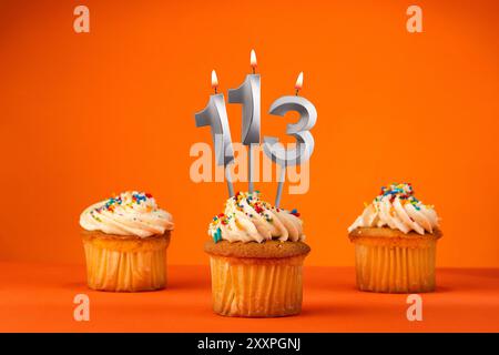 Kerze Nummer 113 - Feier mit Geburtstagskuchen auf orangem Hintergrund Stockfoto